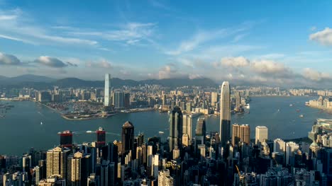 Lapso-de-tiempo-centro-de-la-ciudad-de-Hong-Kong.-Victoria-Harbour-desde-la-cima.-Distrito-financiero-de-ciudad-inteligente.-Rascacielos-y-altos-edificios.-Vista-aérea-con-cielo-azul.