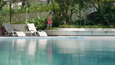 Asia-adolescente-corriendo-y-saltando-en-la-piscina-en-el-jardín-lenta