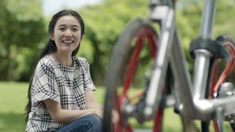 asiatische-Frau-sitzen-und-ausruhen-nach-dem-Radfahren-im-freien