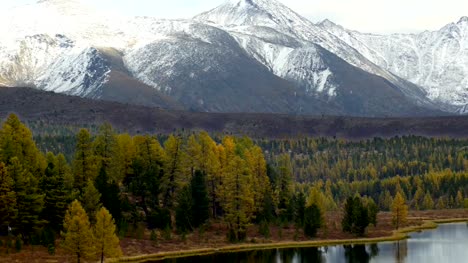 Picos-nevados-por-encima-de-lago-de-montaña-en-otoño-panorámica