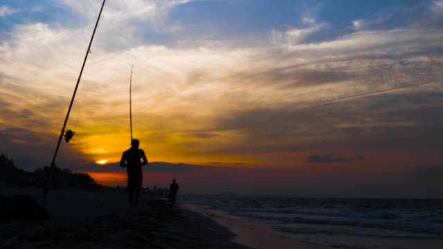 Silhouette-auf-Fischer-bekam-Fisch-beim-Angeln-im-Meer-bei-Sonnenuntergang