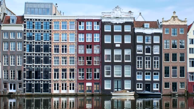 Barcos-en-canal-de-Amsterdam-Damrak-con-reflexión-y-casas.-AMS