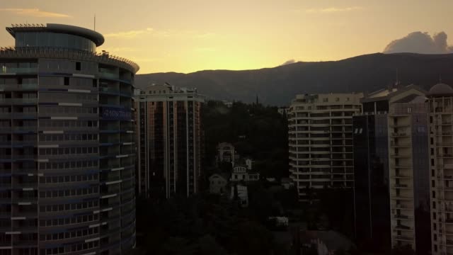 Silhouette-des-hohen-Wolkenkratzer-Gebäude-Wohnungen-leben,-rechtzeitig-ein-Sonnenuntergang-in-der-Nähe-der-Berge-und-Wolken