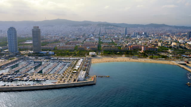 Flying-along-Barcelona-shore-with-city-skyline,-Spain.-Aerial-view