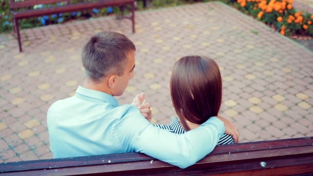 Pareja-romántica-sentado-sobre-un-banco-en-el-parque-durante-el-verano