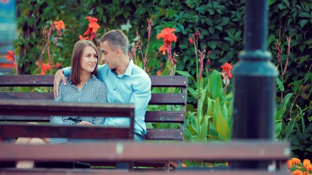 Young-couple-spend-time-together-on-a-bench-in-a-holiday-park