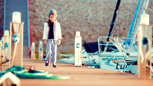 Girl-child-strolls-along-the-marina-for-boats-and-boats
