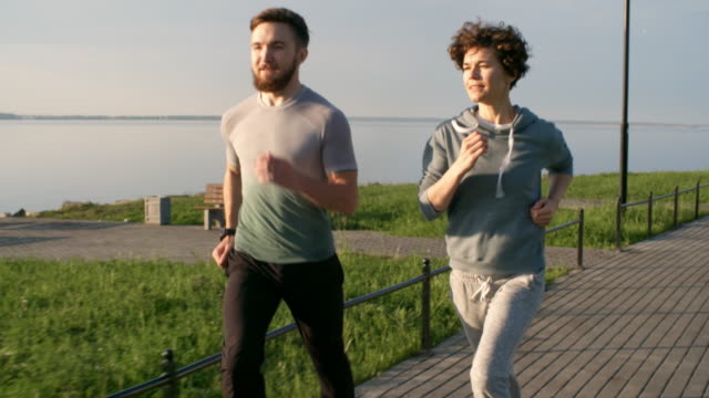 Sportlicher-Mann-und-Frau-im-Freien-an-sonnigen-Tag-laufen