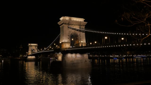 Szechenyi-puente-en-Budapest-sobre-río-que-Danubio-por-noche-4K-2160P-UltraHD-material-de-archivo---puente-famoso-de-la-cadena-situado-en-la-capital-húngara-de-Budapest-iluminado-por-la-noche-4K-video-UHD-de-3840-X-2160