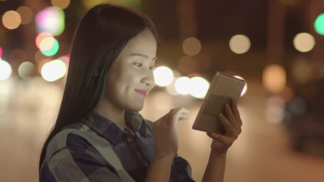 Young-Asian-woman-using-tablet-in-the-city-streets