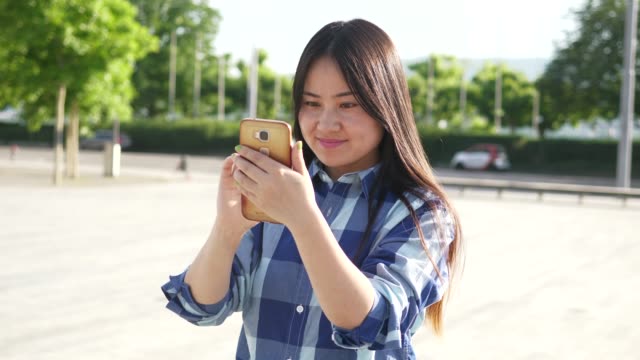 Junge-Asiatin-mit-Handy-in-den-Stadtstraßen