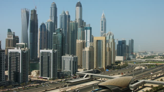 Pan-shot-of-towers-en-una-ciudad,-Dubai,-Emiratos-Árabes-Unidos