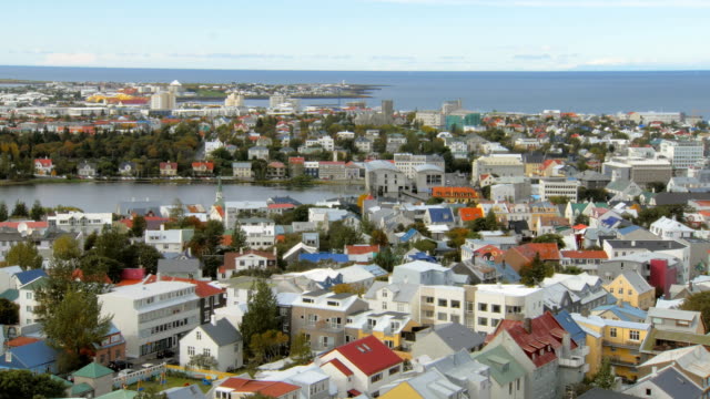vista-superior-en-el-panorama-de-la-ciudad-de-Reykjavik,-lago-Tjornin-y-Océano-Atlántico-en-el-fondo