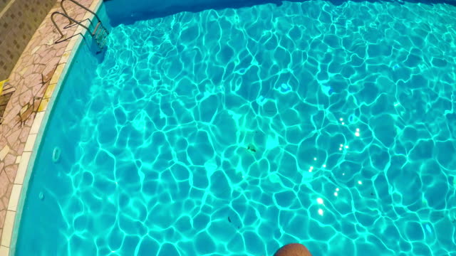 Inmersión-del-hombre-con-la-cámara-de-acción-arriba-de-la-cabeza-en-una-piscina.