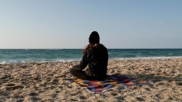 Girl-meditates-on-the-shore-of-the-Mediterranean-Sea-on-a-cool-autumn-day.