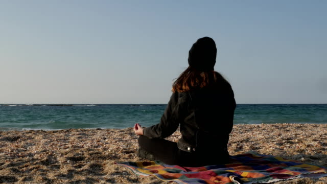 Chica-medita-en-la-orilla-del-mar-Mediterráneo-en-un-fresco-día-de-otoño.