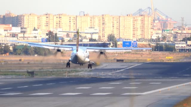 propeller-plane-landing-at-airport-runway,-rear-view