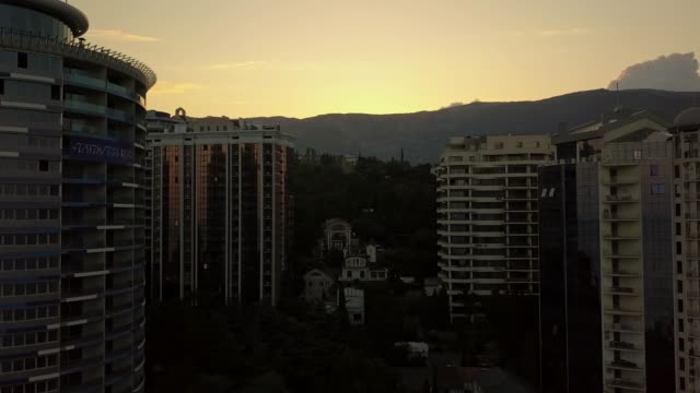 Silhouette-des-hohen-Wolkenkratzer-Gebäude-Wohnungen-leben,-rechtzeitig-ein-Sonnenuntergang-in-der-Nähe-der-Berge-und-Wolken