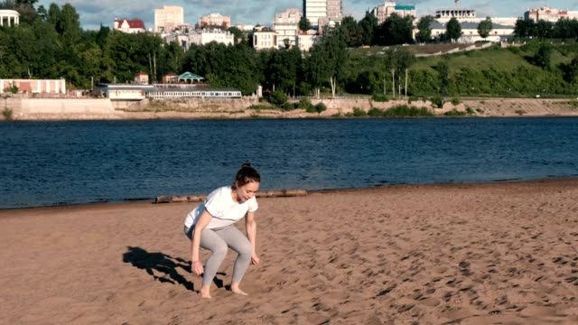 Mujer-haciendo-deportes-ejercicios-a-orillas-del-río-en-la-ciudad.-Saltar-desde-sentado.