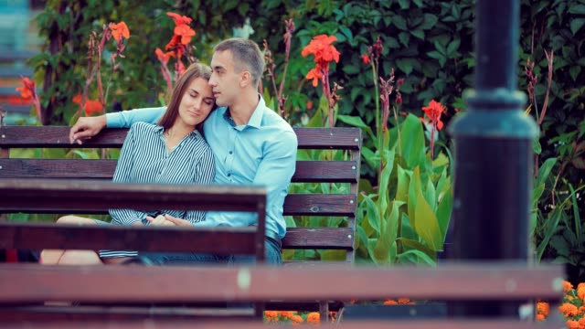 Attractive-couple-sitting-on-bench-in-park