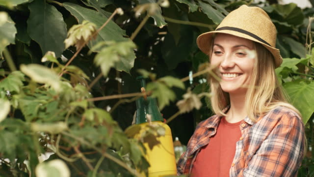 Mujer-feliz-rociando-las-plantas-en-invernadero