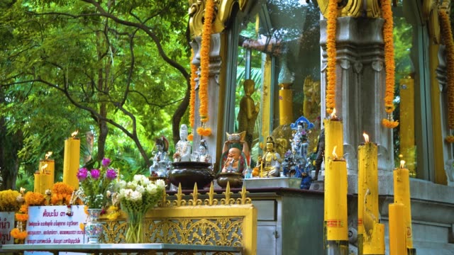 Tempel-Buddha-unter-den-Bäumen.-Buddhismus-in-Asien.-Kerzen-und-Blumen.-Ort-der-religiösen-Verehrung-der-Gläubigen