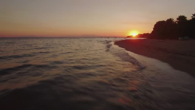 Flug-über-den-Strand-und-das-Meer-mit-Booten-bei-Sonnenuntergang.-Trikorfo-Beach,-Griechenland