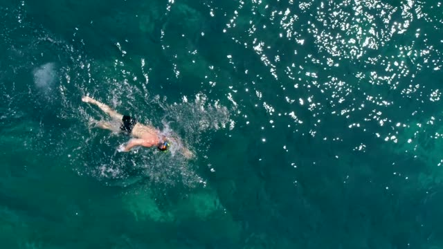 Aerial-view-of-man-swimming-in-the-sea-of-Kioni-island,-Greece
