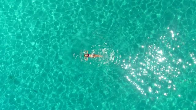 Aerial-view-of-a-woman-swimming-in-the-sea-of-Atokos-island,-Greece
