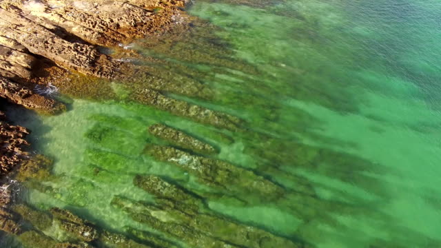 Emerald-ocean-wave-on-a-rocky-beach-aerial-view