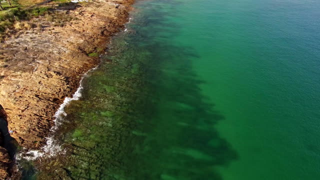 Beautiful-emerald-ocean-wave-on-a-rocky-beach-aerial-view