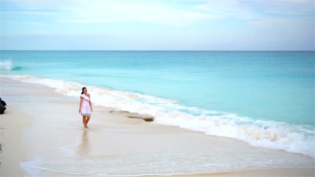 Schöne-junge-Frau-am-Strand-zu-Fuß-in-seichtem-Wasser.