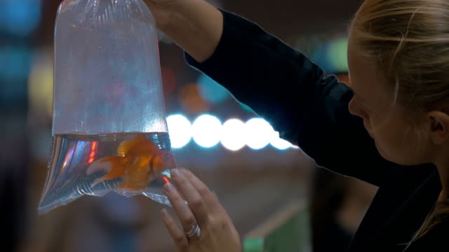 Woman-holds-in-hand-plastic-package-with-aquarium-gold-fish-in-the-shopping-mall.-Hong-Kong,-China