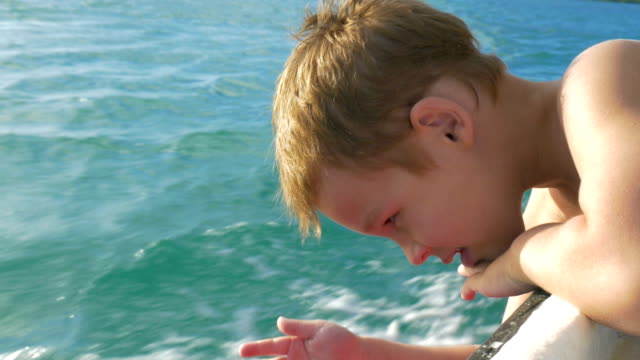 Niño-viaja-en-barco-y-tratar-de-tocar-el-agua