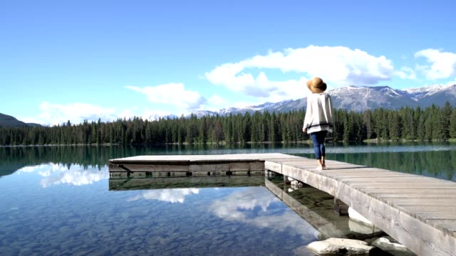 Mujer-caminando-sobre-pie-de-muelle-sobre-el-impresionante-lago-de-montaña-en-las-Rocosas-canadienses