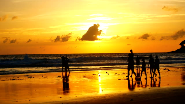 Silhouette-Touristengruppen-sind-Fuß-am-Strand-bei-Sonnenuntergang-beim-Entspannen-am-tropischen-Strand-vor-der-Monsunzeit-mit-Sonnenuntergang-Hintergrund-in-der-Natur-und-Reisen-Konzept.