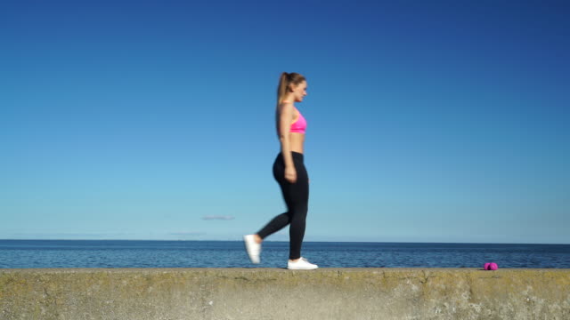 Woman-doing-sports-exercises-outdoors-by-seaside-4K