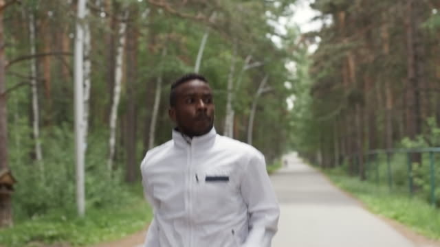 Black-Man-in-Windbreaker-Jogging-in-Forest