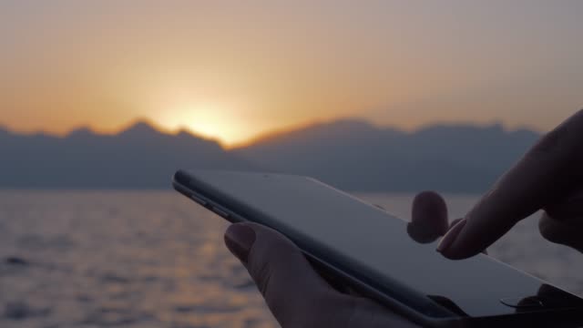 Mujer-con-celular-en-fondo-mar-y-puesta-del-sol