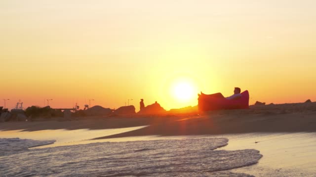 Sonnenuntergang-Szene-des-Mannes-in-aufblasbaren-Liege-am-Meer-entspannen