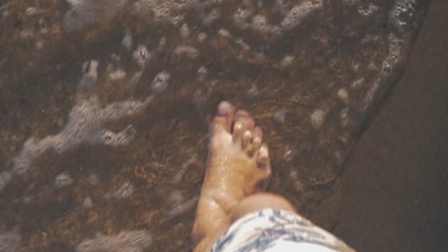 Vacationer-walking-along-the-sea-coast-and-waves-washing-his-feet