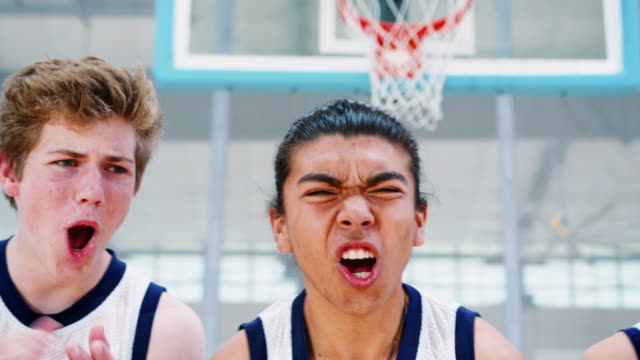 Porträt-von-wettbewerbsfähigen-männlich-High-School-Basketballteam-mit-Trainer-auf-Platz