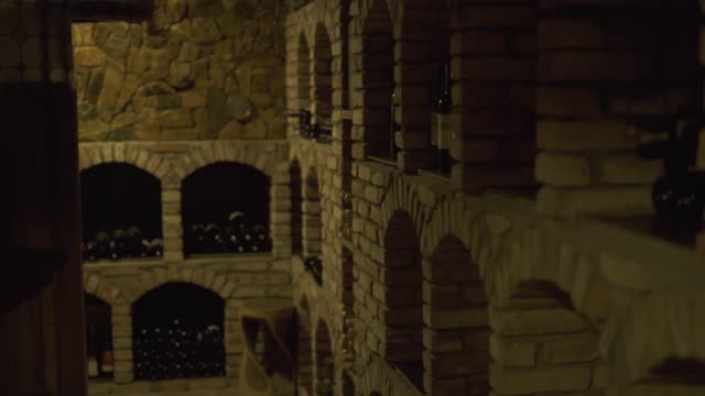 Wine-bottles-lying-in-stack-at-cellar-in-tavern.-Glass-bottles-of-wine-stored-in-stone-cellar-in-restaurant