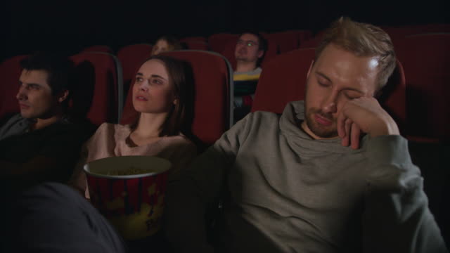 Man-sleep-at-cinema-movie.-Guy-sleeping-at-cinema-date.-People-watch-boring-film