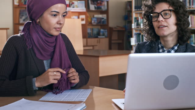 Junge-muslimische-Frau-studieren-mit-Lehrerin