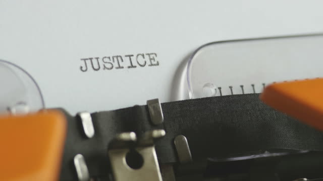 Close-up-footage-of-a-person-writing-JUSTICE-on-an-old-typewriter,-with-sound