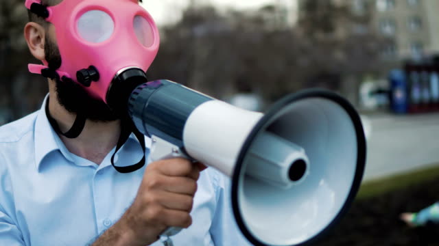 Caucasian-man-in-a-pink-gas-mask-shouts-into-a-megaphone-close-up-4k.
