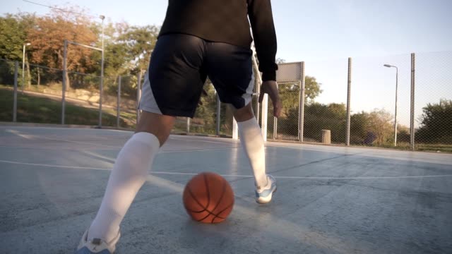 Vista-rara-de-un-jugador-de-baloncesto-niña-formación-y-ejercicio-al-aire-libre-en-la-cancha-local.-Dribling-con-la-pelota,-rebotando-y-hacer-un-tiro.-Tomas-de-ángulo-bajo
