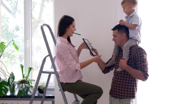 Reparatur-Wohnung,-junge-Familie-mit-Sohn-tun-schmücken-Interieur-und-Dreh-Regal-und-Bild-in-Wohnung