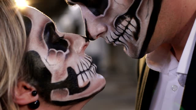 Halloween-loving-couple-with-skull-makeup-looking-at-each-other.